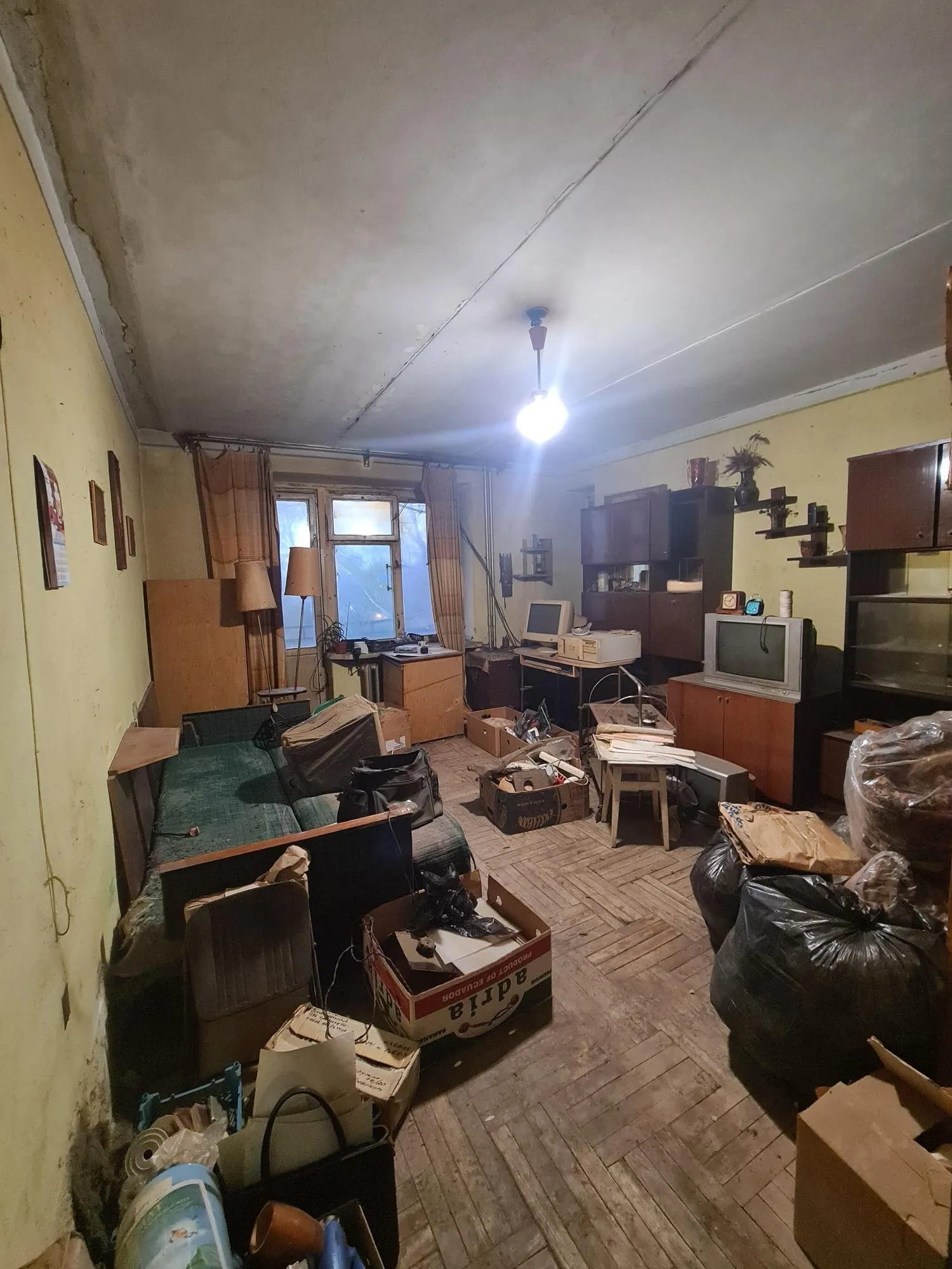 Wohnzimmer einer alten Wohnung, voll mit Möbeln, Kartons und Säcken vor der Auflösung