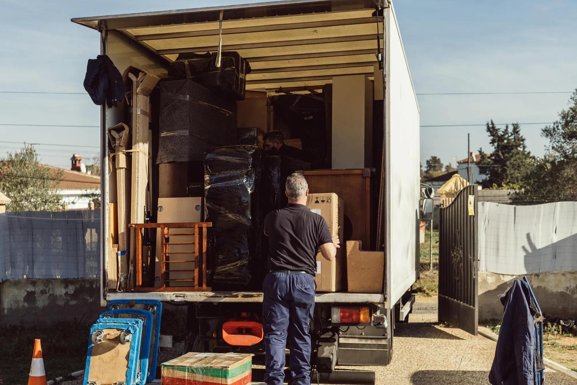 Ein Helfer lädt alte Möbel, Stühle und Schränke in einen Lkw
