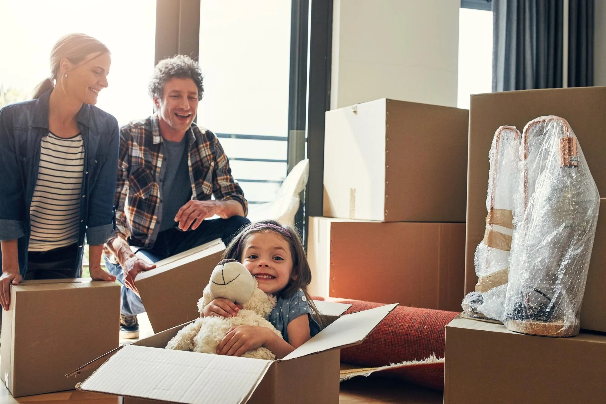 Eine Familie packt in der neuen Wohnung die ersten Kartons aus