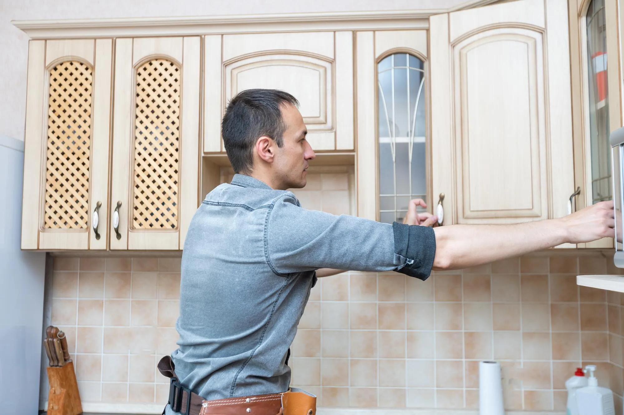 Ein Handwerker hängt in einer Küche die Oberschränke auf