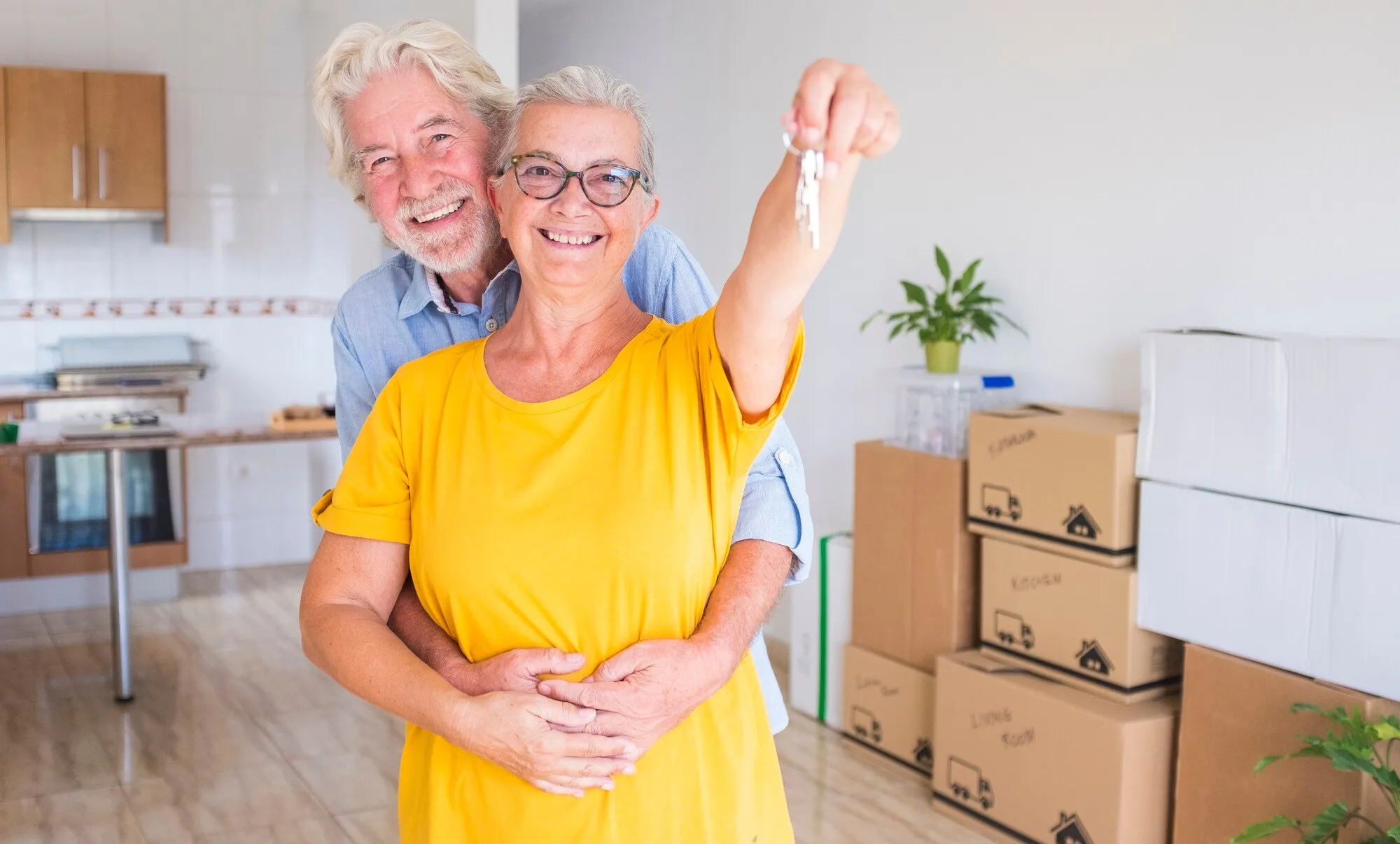 Zufriedenes Seniorenpaar mit Schlüsseln in der neuen Wohnung