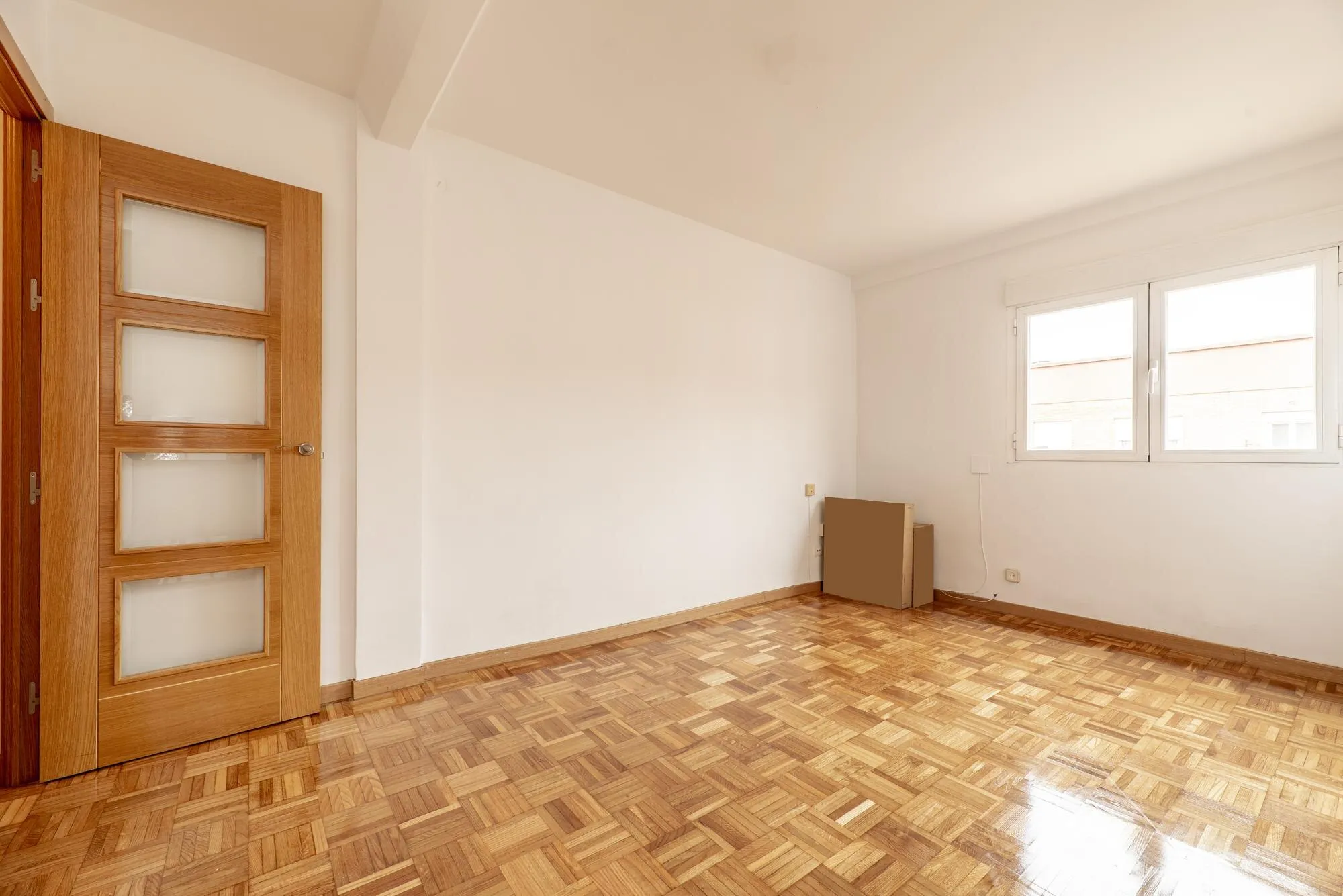 Leeres Wohnzimmer mit Parkett und frisch gestrichenen Wänden